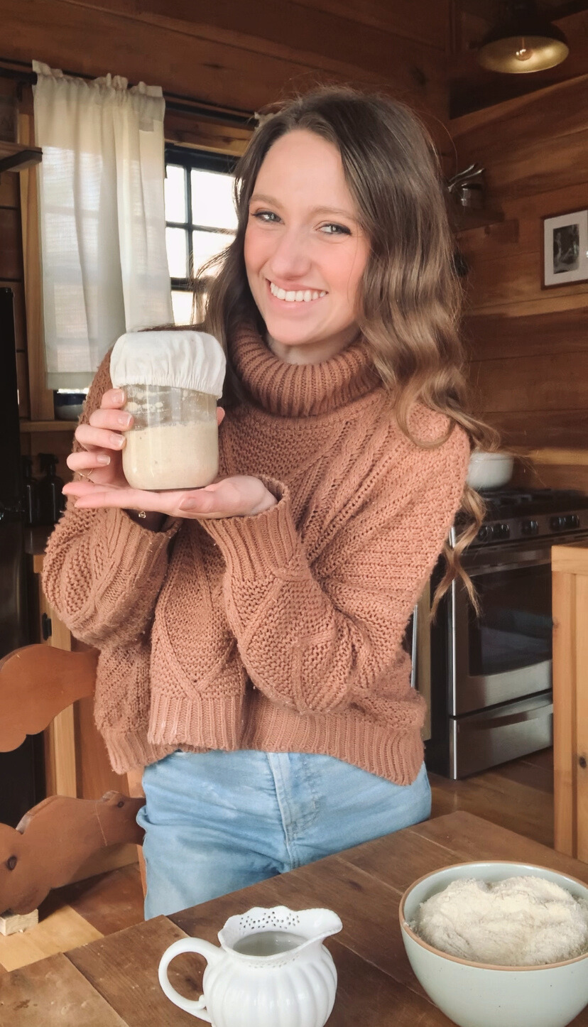 Caitlin holding a warm mug in a cozy cabin
